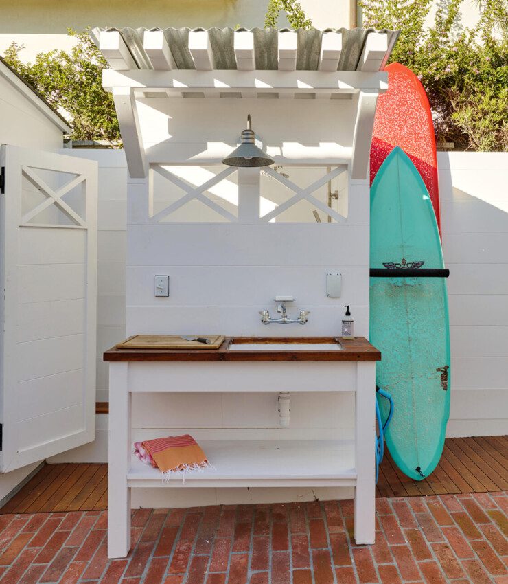 Showcasing the outside area focusing on the custom wash stand and surfboard storage